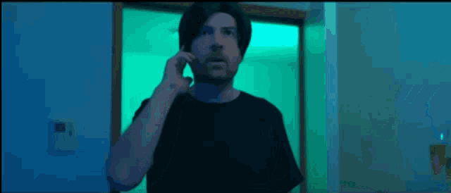 a man in a black shirt is talking on a phone