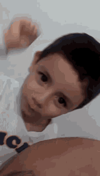 a young boy is laying on a man 's shoulder and looking at the camera .