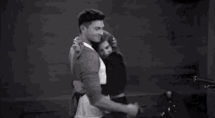 a black and white photo of a man hugging a woman .