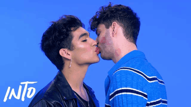 two men kissing in front of a blue background with the word into on the bottom