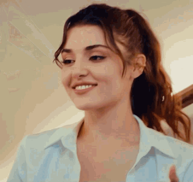 a close up of a woman wearing a white shirt and ponytail smiling .