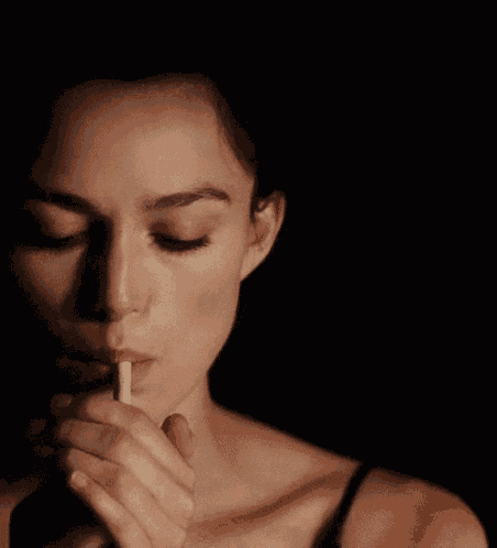 a woman is smoking a cigarette with a black background