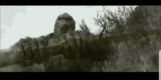 a statue of a gorilla holding a stick in a forest .