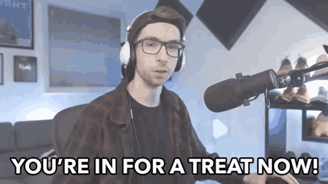 a man wearing headphones and glasses says " you 're in for a treat now " in front of a microphone