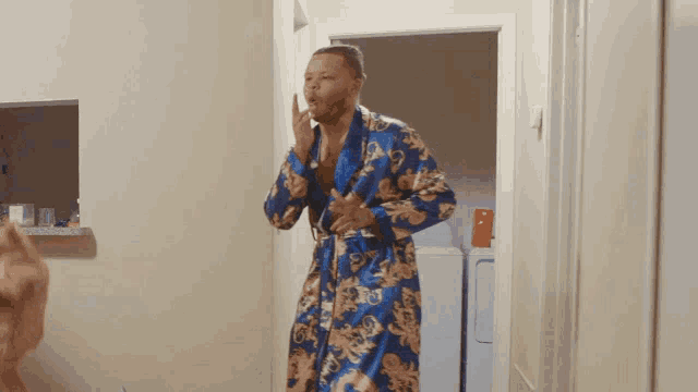 a man in a blue and gold robe is standing in front of a laundry machine