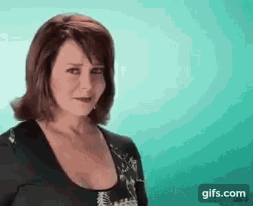 a woman with red hair is making a funny face while standing in front of a blue background .