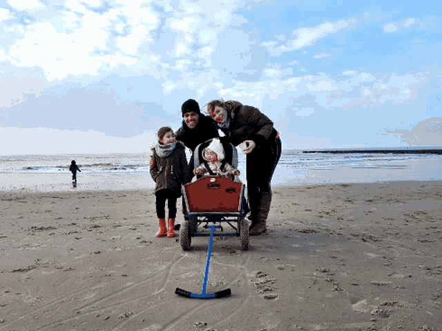 a family posing for a picture on the beach with a wagon