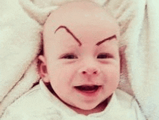 a baby with a drawing of eyebrows on his forehead is smiling .