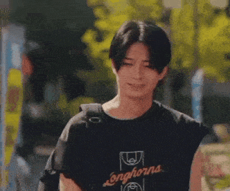 a young man wearing a black t-shirt is walking down a street .