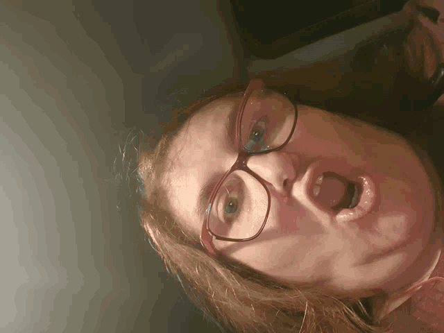 a woman with glasses making a funny face with her mouth open