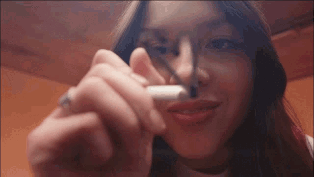 a close up of a woman smoking a cigarette with a marker on her nose .