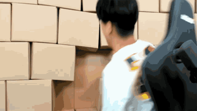 a man in a white shirt is standing in front of a wall of boxes