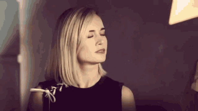 a woman with her eyes closed wearing a black top