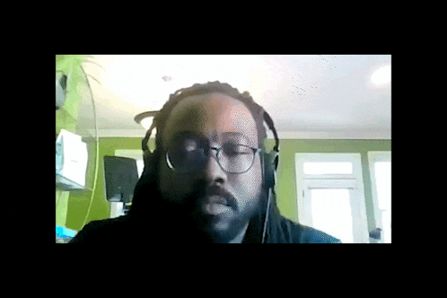 a man wearing headphones and glasses is looking at the camera