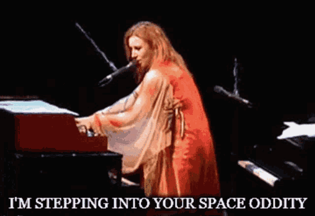 a woman in a red dress is playing a piano and singing into a microphone