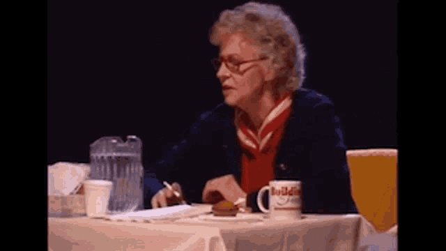 a woman sits at a table with a bulldogs mug