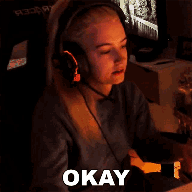 a woman wearing headphones says okay in front of a computer