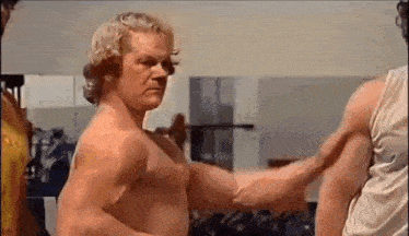 a man is flexing his muscles in a gym .