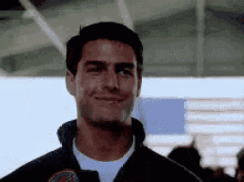 tom cruise is smiling and looking at the camera while wearing a jacket .
