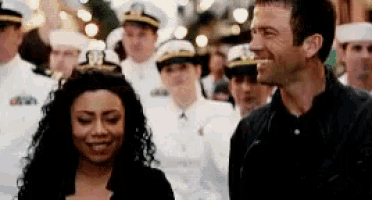 a man and a woman are standing next to each other and smiling in front of a crowd of people .