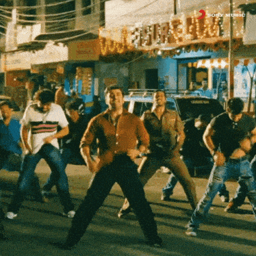 a group of men are dancing on a street in front of a sign that says ' sony music '