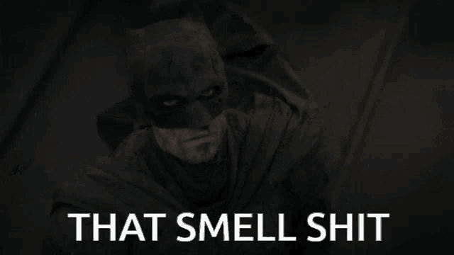 a black and white photo of batman with the words that smell shit below him