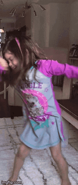 a little girl wearing a purple shirt that says unicorn is dancing in a living room