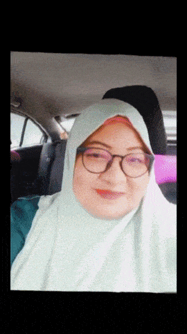 a woman wearing glasses and a hijab is smiling in the back seat of a car