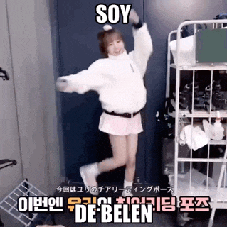 a girl in a white jacket and pink skirt is dancing in a room with a sign that says soy de belen .