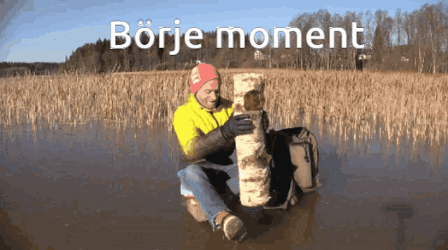 a man in a yellow jacket is sitting in the water holding a birch log with the words borje moment written on the bottom