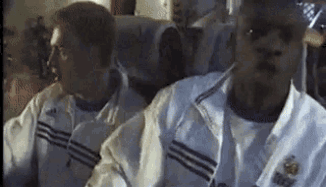 two men are sitting on a plane wearing white jackets and shirts .