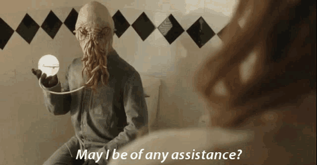 a man in a squid mask is sitting on a toilet with the words may i be of any assistance above him