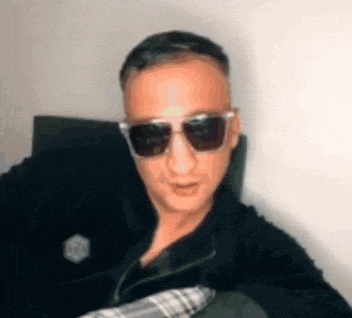 a man wearing sunglasses is sitting in a chair .