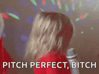 a woman in a red dress is singing into a microphone and says pitch perfect , bitch .