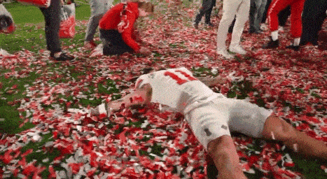 a football player is laying on the ground in confetti .
