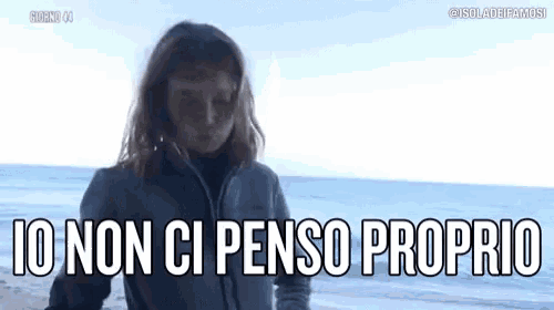 a woman is standing on a beach with the words `` io non ci penso proprio '' written on the bottom .