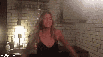 a woman in a black tank top is dancing in a kitchen