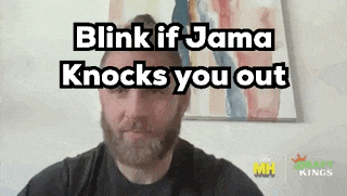 a man with a beard is talking on a video call with the words `` blink if jama knocks you out '' above him .