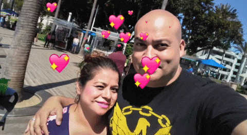 a man and a woman are posing for a picture and the man is wearing a shirt with the letter m on it