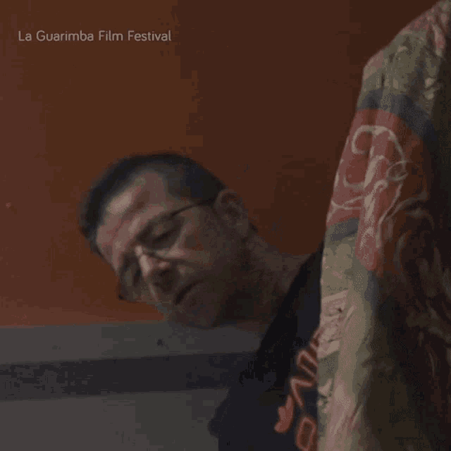 a man in a black shirt is standing in front of an orange wall with la guarimba film festival written on it