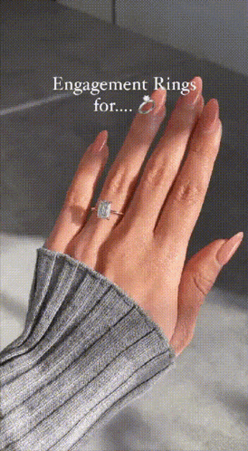 a close up of a woman 's hand with an engagement ring on her finger