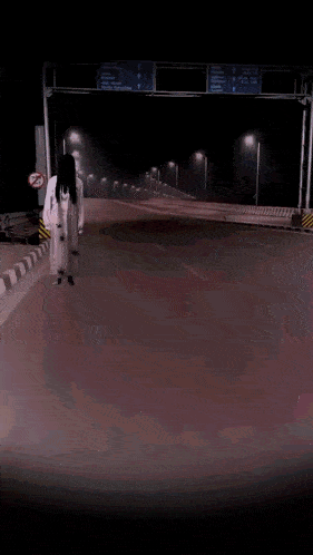 a woman in a white dress is walking down a highway