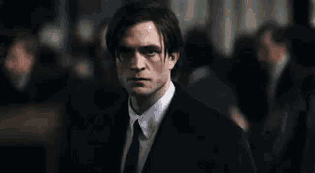 a man in a suit and tie is looking at the camera .