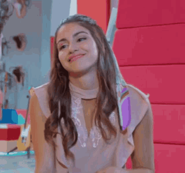 a young woman in a pink dress is smiling and looking at the camera .