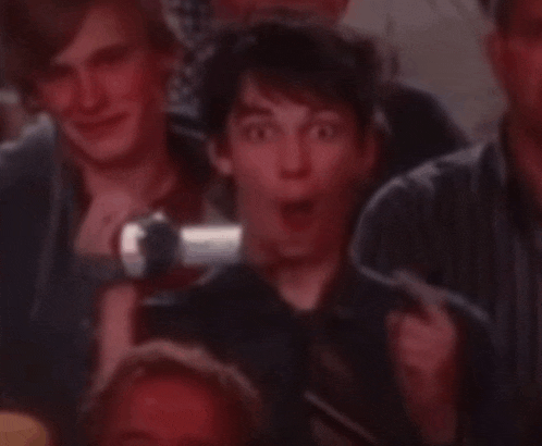 a group of people are sitting in a dark room and one of them is making a surprised face