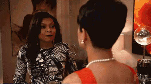 a woman in a red dress is looking at herself in a mirror