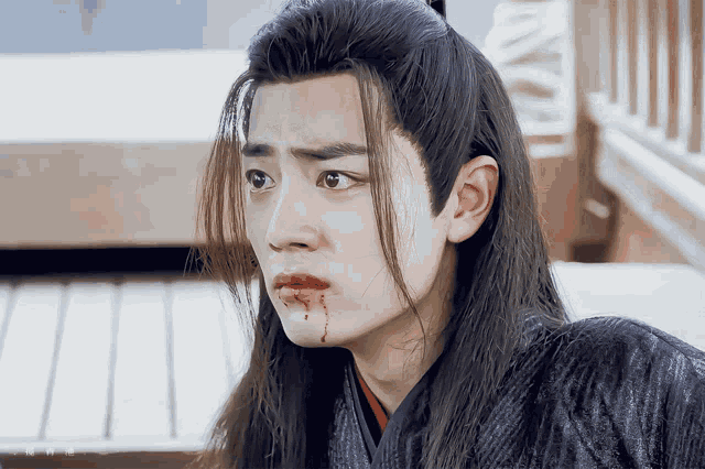 a young man with long hair has blood on his mouth