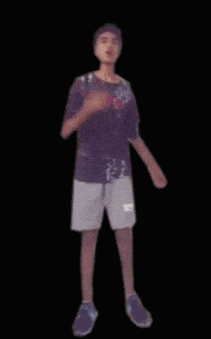 a man in a purple shirt and white shorts is dancing