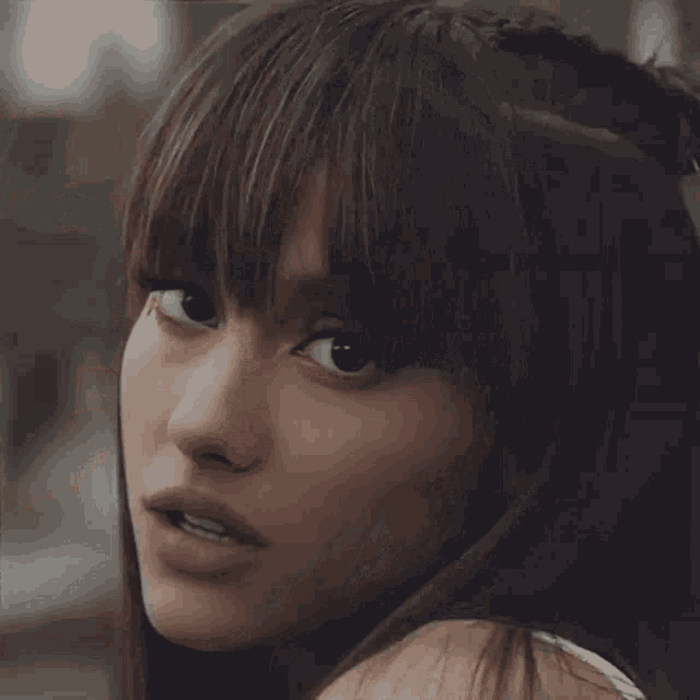 a close up of a woman 's face with long hair and bangs .