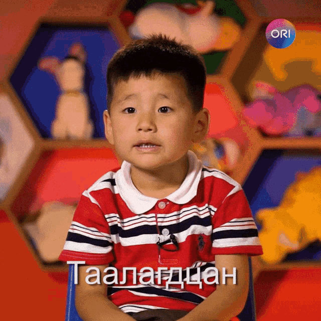 a young boy is sitting in front of a display of stuffed animals and the word ori is on the bottom